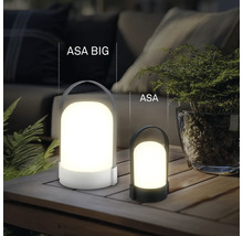 Dve rôzne veľké prenosné LED stolové lampy ASA BIG a ASA na drevenom stole vonku s rastlinami a čalúneným nábytkom.