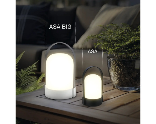 Dve rôzne veľké prenosné LED stolové lampy ASA BIG a ASA na drevenom stole vonku s rastlinami a čalúneným nábytkom.