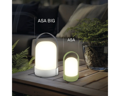 Dve moderné prenosné LED stolné lampy ASA BIG a ASA z plastu na drevenom stole vo svetlom, organizovanom vonkajšom priestore.