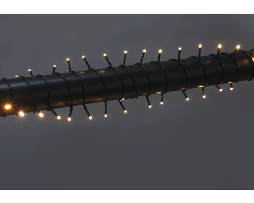LED svetelná reťaz s teplými bielymi diódami, omotaná okolo tmavej rúry.