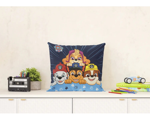 Dekoračný vankúš Paw Patrol s motívmi postáv Marshall, Chase, Rubble a Skye na komode v detskej izbe.