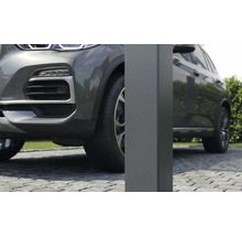 Detailný záber na štvorcový kovový stĺpik pre prístrešok pre auto na dláždenej príjazdovej ceste vedľa sivého auta.