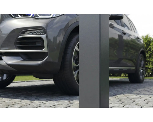 Detailný záber na štvorcový kovový stĺpik pre prístrešok pre auto na dláždenej príjazdovej ceste vedľa sivého auta.