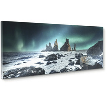 Obraz na plátne v panoramatickom formáte so skalnými útvarmi Reynisdrangar na Islande pod polárnou žiarou.