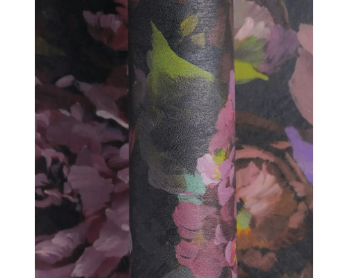 Detailný záber na rolku vliesovej tapety s veľkým kvetinovým vzorom v ružových, fialových a zelených tónoch na tmavom pozadí, štruktúrovaný povrch.