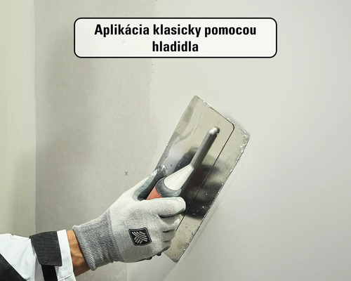 Nanášanie stierky na stenu pomocou hladidla.