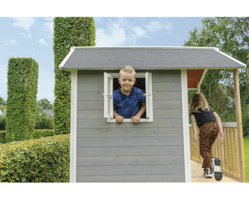 Detský hrací domček s dieťaťom v okne a dievčaťom na verande v záhrade