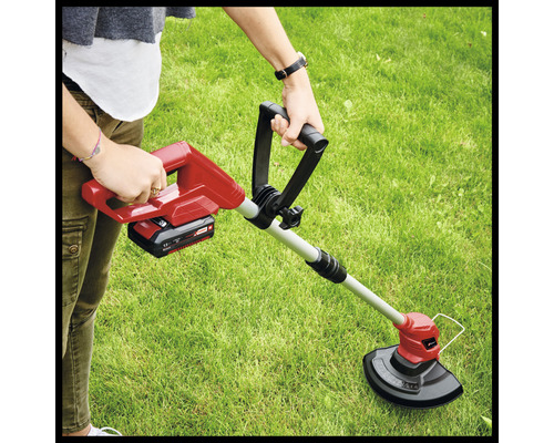 Pohľad zhora na osobu tlačiaci akumulátorový vyžínač na trávnik