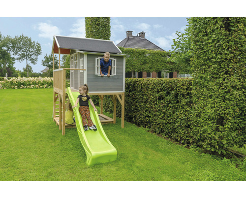 Detský domček so šmýkačkou v záhrade s deťmi