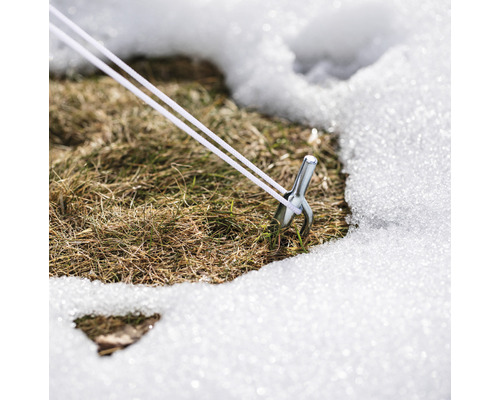 Kolík s napínacím lankom v snehu na trávniku