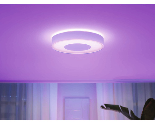 Okrúhle stropné svietidlo v miestnosti s farebným osvetlením.