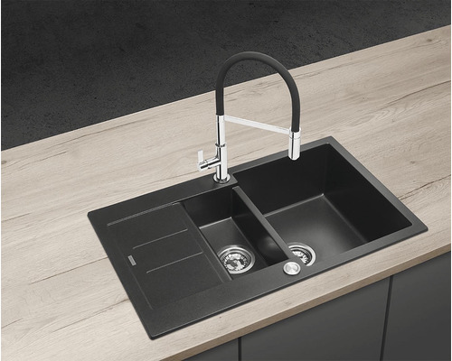 Čierny kuchynský drez s odkvapkávacou plochou a vodovodnou batériou na pracovnej doske