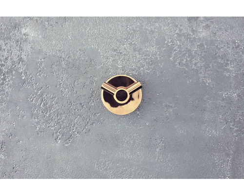 Zlatý nábytkový gombík na sivom povrchu