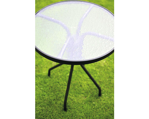 Okrúhly záhradný stôl so sklenenou doskou a kovovým rámom na trávniku