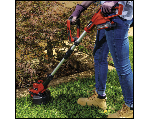 Osoba obsluhuje akumulátorový vyžínač v záhrade.