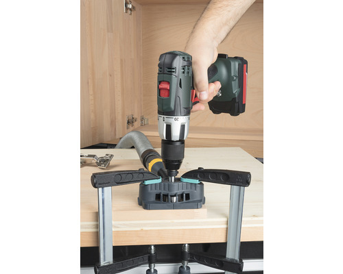 Vŕtačka so šablónou vŕta otvor do drevenej dosky.