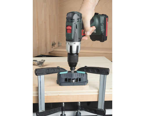 Akumulátorový skrutkovač vŕta otvory pre kus nábytku pomocou vŕtacej šablóny