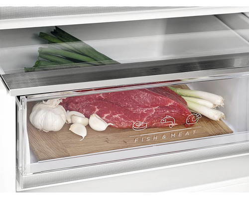 Detailný záber chladničky so zásuvkou na ryby a mäso, plnou hovädzieho mäsa, cesnaku a jarnej cibuľky.