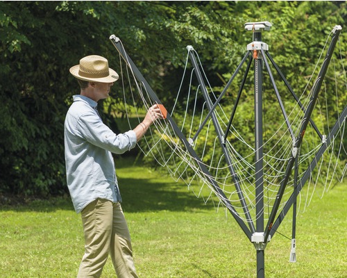 Muž obsluhuje vonkajší sušiak na bielizeň v záhrade