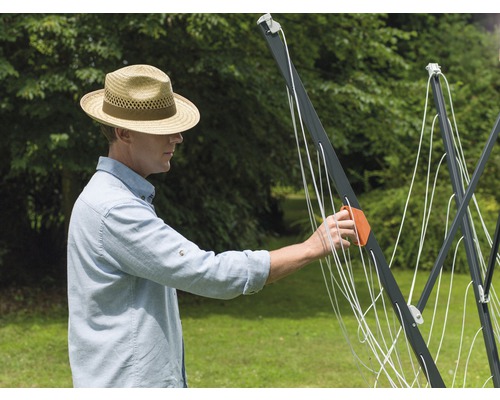 Muž rozkladá vonkajší otočný sušiak na bielizeň.