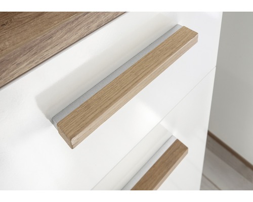 Detail bielej skrine s drevenými úchytkami.