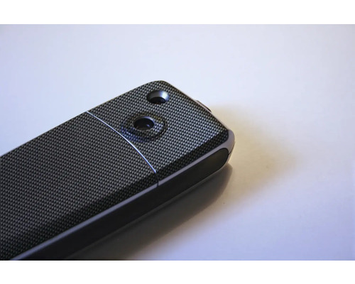 Detailný pohľad na elektronické zariadenie so vzorom uhlíkových vlákien a dvoma vybraniami.