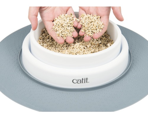 Podstielka pre mačky v bielej miske s podložkou a rukami, ktoré držia podstielku