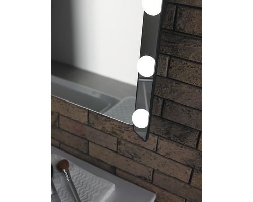 Detail osvetleného zrkadla vedľa tehlovej steny v kúpeľni