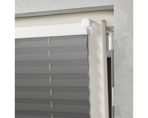 Detail šedej plisovanej žalúzie v okne.