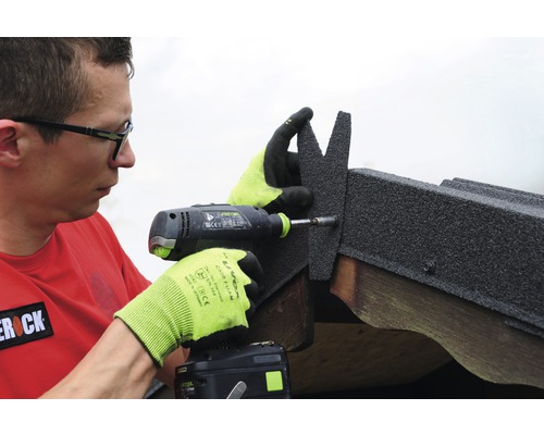 Muž pripevňuje strešné šindle pomocou akumulátorového skrutkovača