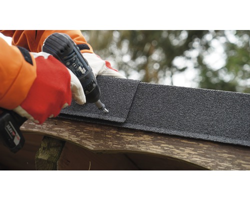 Osoba pripevňuje bitúmenový šindeľ pomocou akumulátorového skrutkovača