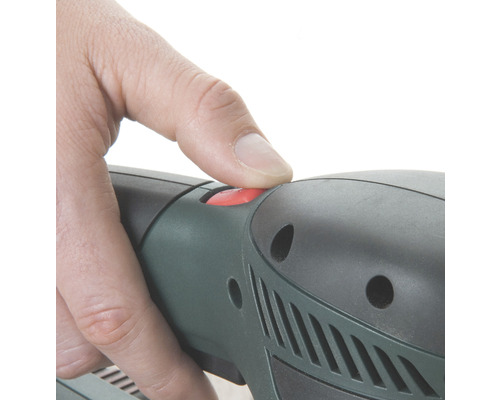 Detailný záber ruky stláčajúcej červené tlačidlo na elektrickom náradí.