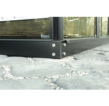 Detailný záber kovového rámu skleníka so skrutkami na kamennej dlažbe. Logo Vitavia.