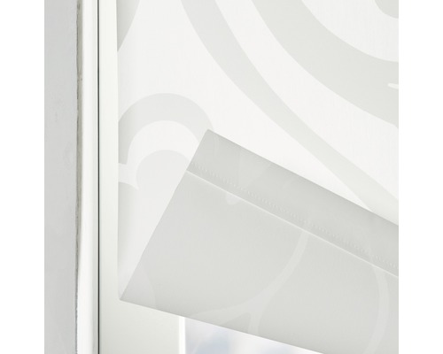 Detailný záber bielej rolety so vzorom v okennom ráme