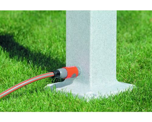 Záhradná hadica pripojená k vodnému stĺpiku na trávniku