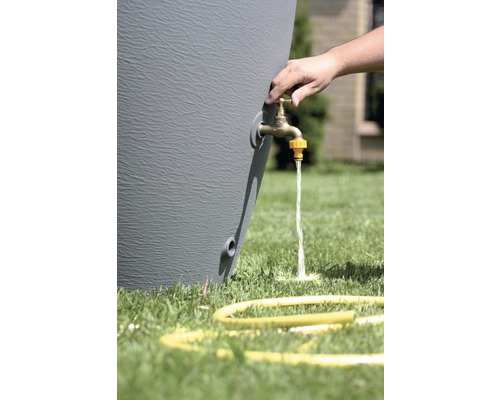 Detailný záber suda na dažďovú vodu s kohútikom v prevádzke a žltou hadicou na trávniku