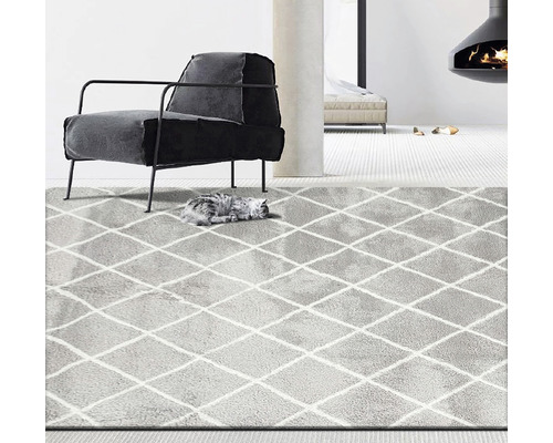 Sivý koberec s kosoštvorcovým vzorom v obývacej izbe s kreslom a krbom.