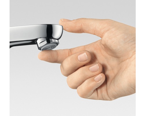 Detail ruky dotýkajúcej sa výtoku vodovodnej batérie.