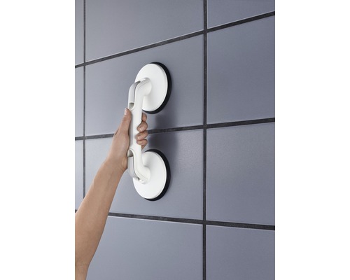 Ruka drží madlo s prísavkou na stene