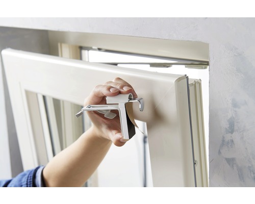 Osoba montuje okno pomocou upevňovacej spony