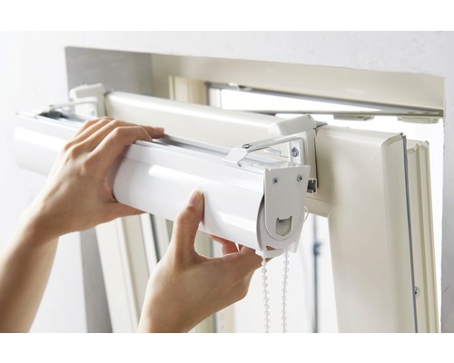 Osoba montuje roletu na okenný rám