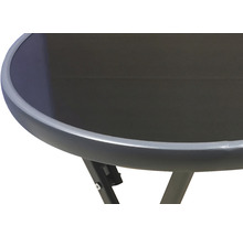 Detail záhradného stola s okrúhlou sklenenou doskou a kovovým rámom