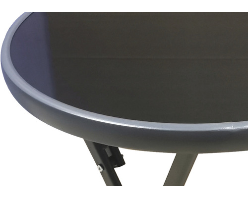 Detail záhradného stola s okrúhlou sklenenou doskou a kovovým rámom