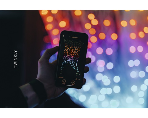 Ruka drží smartfón s aplikáciou Twinkly pred svetlami