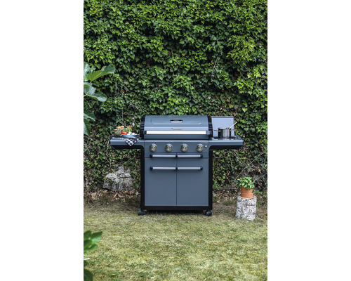 Tmavosivý plynový gril so štyrmi horákmi a bočnými stolíkmi v záhrade
