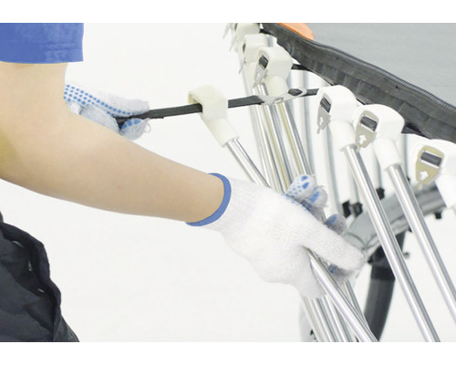 Osoba v rukaviciach montuje sušiak na bielizeň.