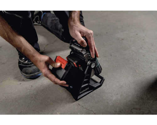 Pohľad zhora na osobu vkladajúcu batériu do stavebnej lampy Metabo.