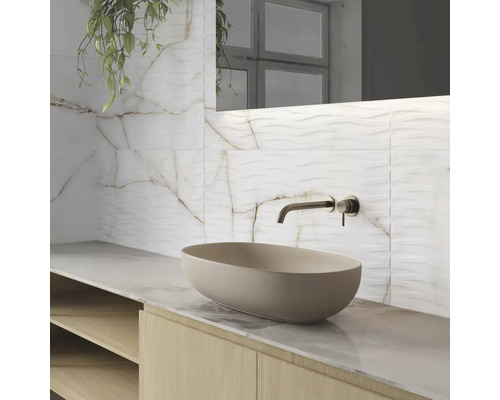 Kúpeľňa s umývadlom na dosku, vodovodnou batériou a obkladom stien s mramorovým vzhľadom.