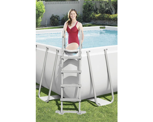 Žena lezie po rebríku do obdĺžnikového bazéna v záhrade