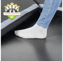 Detailný záber trampolíny so systémom ochrany nôh a osoby v ponožkách.